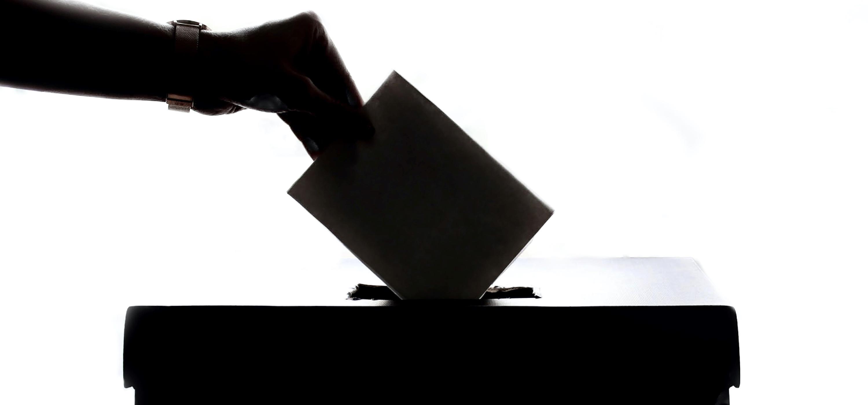 Hand placing envelope in ballot box